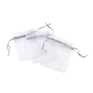 Close-up detail view of sheer organza drawstring gift bags in soft light grey color.