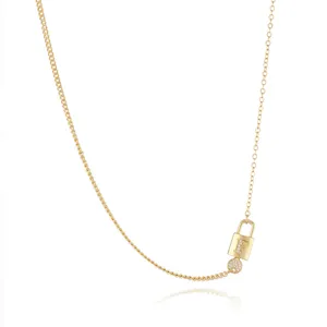 Gold plated asymmetric chain necklace detail featuring an initial lock pendant with cubic zirconia.