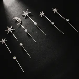 Gros plan détaillé de pinces à cheveux étoiles et lune en strass scintillants sur fond sombre.