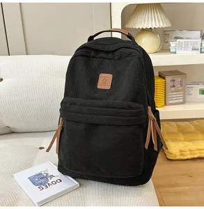 Dettaglio zaino in corduroy nero con tasca frontale con cerniera e patch in vera pelle.