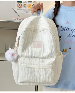 Vue détaillée d'un sac à dos blanc plissé avec joli porte-clés chat duveteux pour femmes.