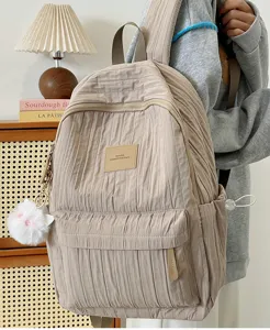 Sac à dos scolaire beige plissé et décontracté pour les étudiants avec un joli pompon moelleux.