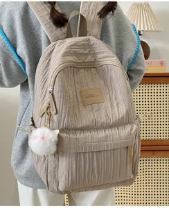 Gros plan d'un sac à dos plissé décontracté avec pendentif en peluche duveteux pour le quotidien.