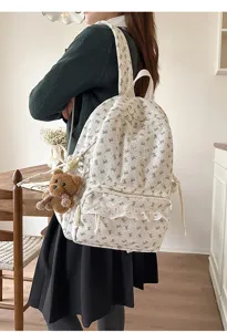Detail view of a cute corduroy backpack featuring bow prints, lace pocket trim, and bear charm.