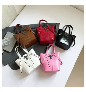 Vista detallada de bolsos tipo cubo estilo punk multicolor con cruz de metal y tachuelas.