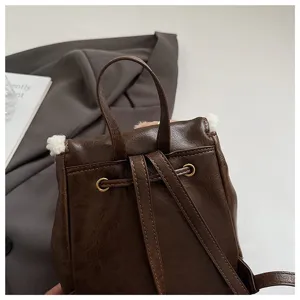 Retro brown mini leather backpack detail featuring cozy plush trim and shoulder straps.