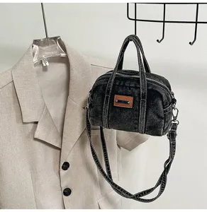 Detail view of the washed denim boston crossbody bag with twin top handles and strap.