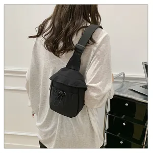 Detail view of a black lightweight crossbody chest bag with drawstring pocket and wide strap.