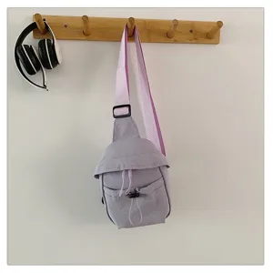 Detailed view of a light purple casual crossbody bag hanging on a wall hook, showing its strap.