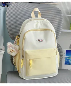 Cute colorblock backpack with furry bear pendant, stylish and spacious student school bag.