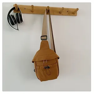 Close-up details of the brown outdoor sling bag showing adjustable strap and drawstring pocket.