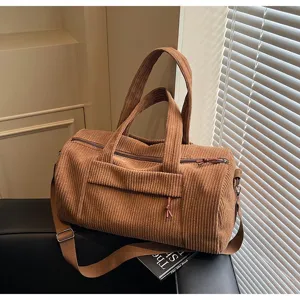 Primo piano di una borsa da viaggio in velluto a coste marrone con dettagli in metallo.