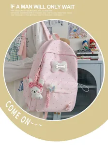 Vue rapprochée du sac à dos à pois roses avec de charmants pendentifs lapin et os en détail.