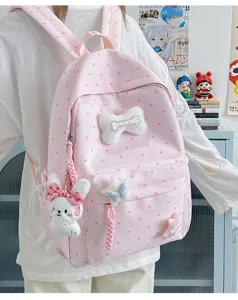 Détail de sac à dos rose à pois avec joli lapin en peluche et nœud dans un style mignon.