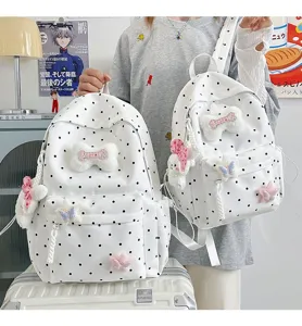 Gros plan de jolis sacs à dos à pois blancs avec pendentifs en peluche os et étoile.