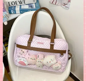 Borsa ita a pois rosa con tasca frontale trasparente, manici marroni e esposizione di peluche.