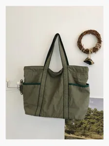 Green nylon tote bag detail showing large capacity, double handles and daily commute use.