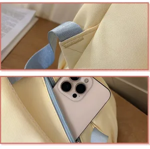 Close-up detail shot of the backpack strap reinforcement stitching and front zipper pocket.