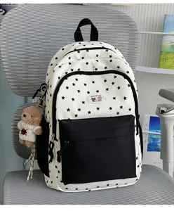 Detailed view of white and black star pattern backpack featuring front pocket and cute bear charm.