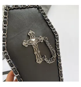 Gothic coffin bag detail showing black leather, woven chain border, and ornate cross hardware.