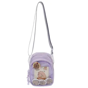 Purple ita bag detail showing transparent front pocket and cute capybara badges and inserts.