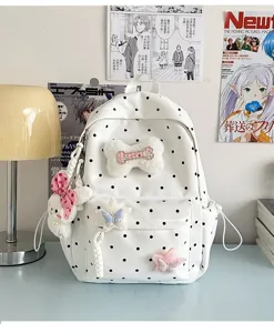 Vue détaillée du joli sac à dos blanc à pois avec poupée en peluche et décoration en os.