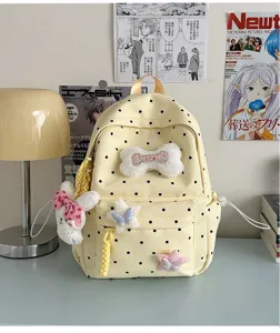 Vue détaillée du sac à dos à pois jaunes avec lapin en peluche et breloques.