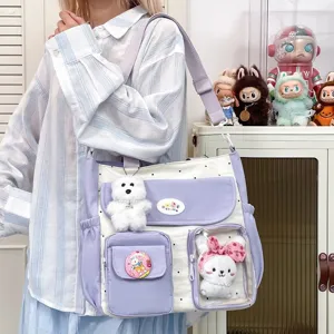Cute canvas shoulder bag detail showing clear window pocket, plush toy, and polka dot design.