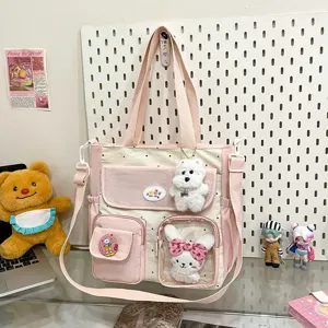 Detail view of the pink and white polka dot canvas tote bag featuring multi pockets and cute plush charms.