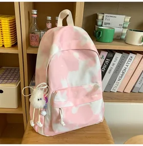 Vista dettagliata zaino tie-dye rosa con tasca frontale e grazioso ciondolo in peluche.