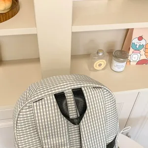 Vista dettagliata dello zaino a quadri con maniglia e spallacci, borsa scolastica casual.