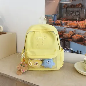Dettaglio zaino giallo carino, tasca frontale trasparente, ricamo con fiocco e simpatici peluche.