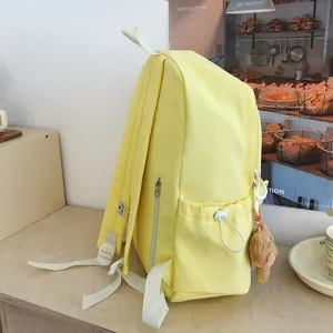 Vista dettagliata dello zaino giallo in tela con tasca laterale e ciondolo in peluche.