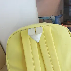 Primo piano della maniglia superiore dello zaino giallo e dei dettagli delle spalline.