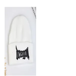 Vue détaillée du bonnet en tricot blanc hiver avec broderie de lettres gothiques.