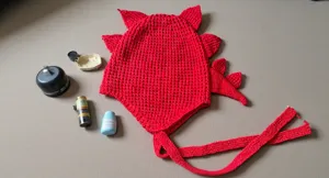 Gorro de punto rojo de invierno con púas de dinosaurio y lazos largos para días fríos.