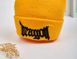 Gros plan détail d'un bonnet en tricot jaune vif avec une broderie gothique noire.