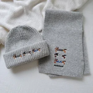 Detailed view of grey knitted scarf and beanie hat set with cute dachshund embroidery.