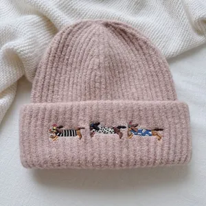 Close-up detail of the cute pink knit beanie featuring adorable embroidered dachshund dogs.