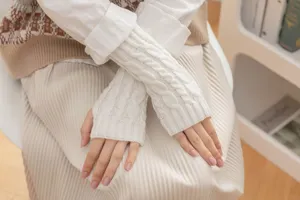 Detail shot of white cable knit fingerless gloves, winter warm half finger hand wear.