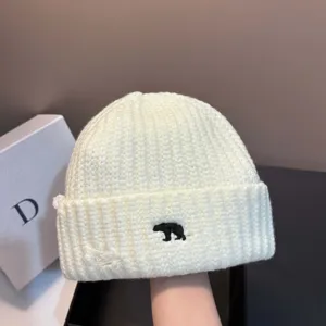 Detail van witte gebreide muts met schattige zwarte ijsbeer borduurwerk voor winter.