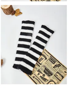 Black and white striped knit arm warmers, cozy fingerless sleeve details for winter warmth.