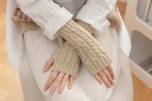 Close-up detail of beige cable knit fingerless gloves, warm winter fashion accessory for hands.