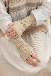 Close-up detail of cozy beige cable knit fingerless gloves, perfect for autumn and winter wear.