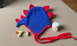 Cálido gorro de punto de dinosaurio con púas rojas y correas largas para el invierno frío.