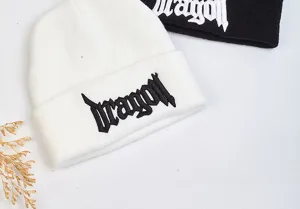 Gros plan de bonnets tricotés d'hiver confortables en noir et blanc avec broderie gothique cool.