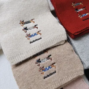 Detailed view of cute dachshund embroidered knit scarf texture, soft wool blend winter warmth accessory.