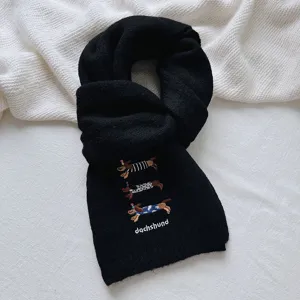 Close-up detail of a black knitted scarf featuring cute embroidered dachshund dogs and text.