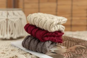 Detailed view of cozy knit fingerless gloves in neutral and rich tones, perfect for winter style.