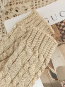 Detailed shot of beige cable knit fingerless gloves, soft wool winter warm arm warmers.